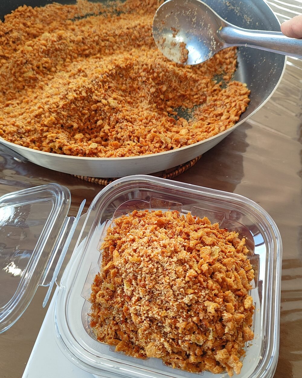 Panela de farofa sendo passada para o pote sobre a balança